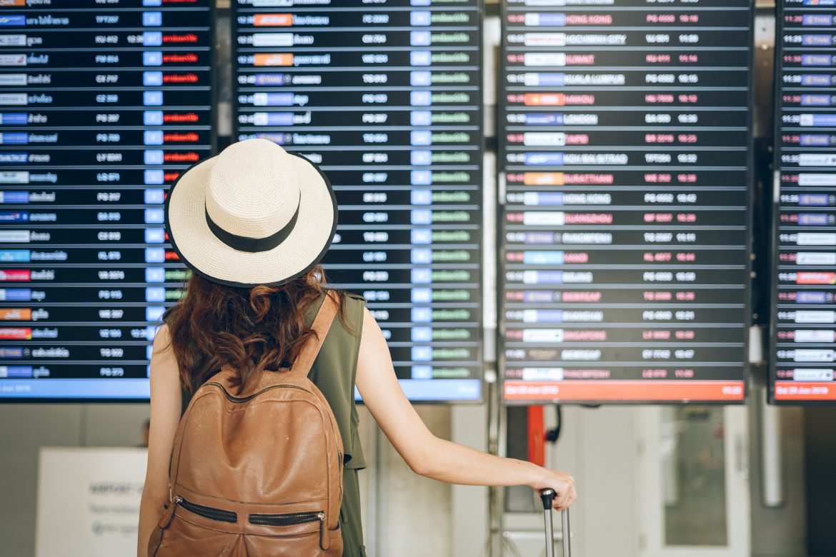 Rear View Of Woman In Hat Looking At Arrival Departure Board